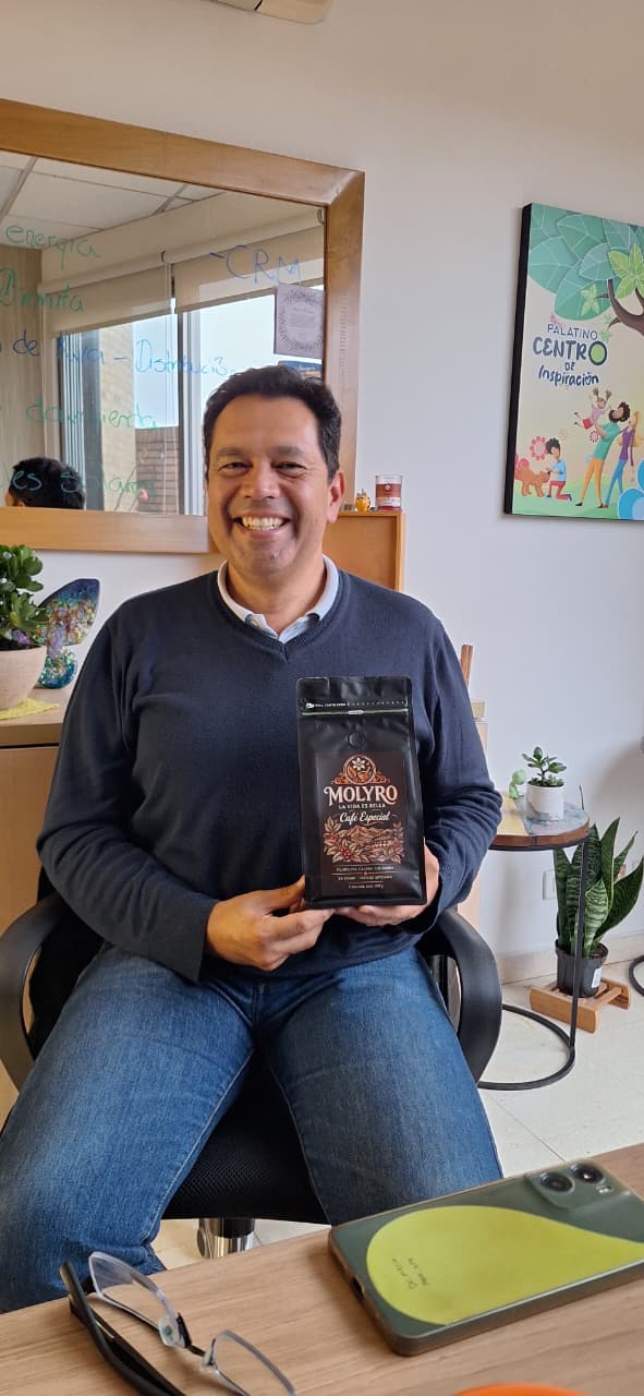 Cliente sonriente sentado sostiene una bolsa de Café Molyro