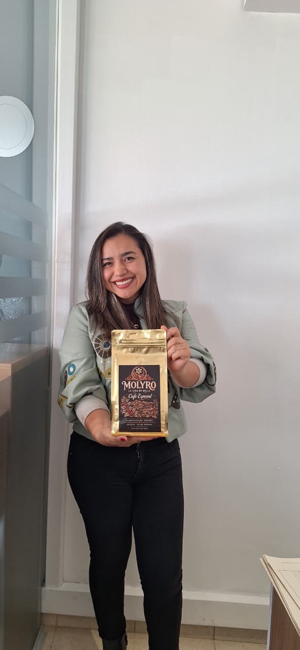 Cliente sonriente sostiene una bolsa dorada de Café Molyro